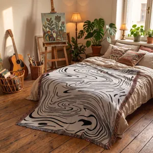 Couverture bohème tissée avec des spirales noires abstraites et des franges colorées.