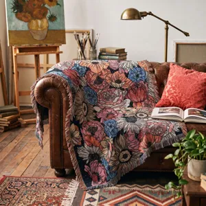 Detailansicht einer gewebten Vintage-Blumendecke, die über ein Ledersofa im Atelier fällt.