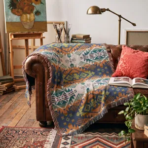 Manta tejida de estilo bohemio colocada sobre un sofá de cuero marrón en estudio.