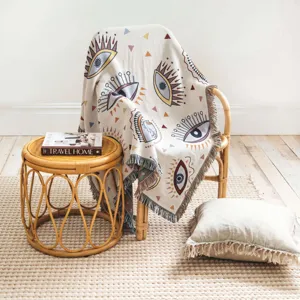 Détail d'une couverture bohème avec motif d'oeil coloré sur une chaise en rotin