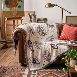 Couverture bohème tissée avec motif œil et franges drapée sur un canapé en cuir vintage