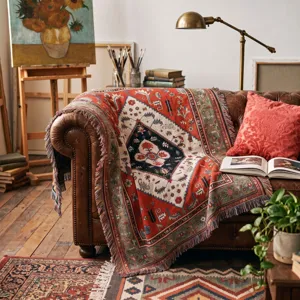 Bohemian woven throw blanket with ethnic patterns and fringe, draped on a leather sofa.