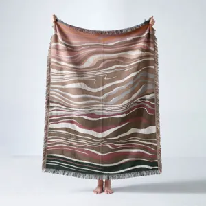 Bohemian style woven throw blanket featuring an abstract wavy pattern and decorative fringe