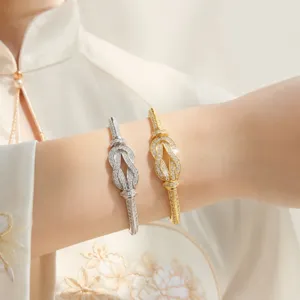 Close-up detail shot of exquisite paved diamond knot bangles worn gracefully on a wrist.