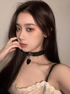 Close-up detail view of a black heart choker necklace on a model, showing metal ring texture.