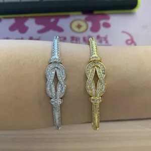 Detailed view of pavé set crystal infinity knot bangles in silver and gold tone finishes.