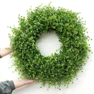 Close-up view of a large lush green artificial boxwood wreath being held for size scale