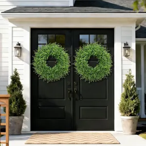 Artificial boxwood wreaths hanging on black double doors for house decoration