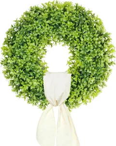 Artificial green boxwood wreath with a cream-colored fabric bow for front door decor