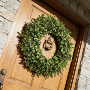 Lush artificial green boxwood wreath hanging beautifully on a rustic wooden front door
