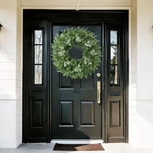 Lush green artificial eucalyptus wreath with white flowers hanging on a black front door