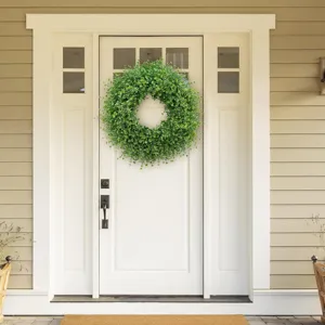 Detail of realistic artificial boxwood wreath hanging on a white classic front door