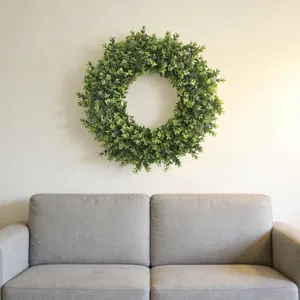 Lifelike artificial boxwood wreath displayed on a wall in a modern living room setting