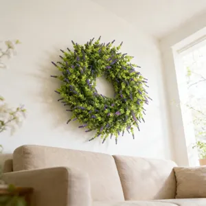 Detailed view of an artificial lavender and boxwood wreath hanging on a minimalist white wall.