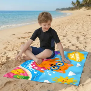 Kind sitzt auf schnelltrocknendem Strandtuch aus Mikrofaser mit Cartoon-Katze am Strand