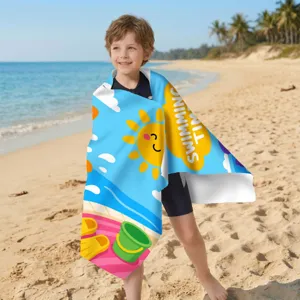 Kind am Strand eingewickelt in ein Mikrofaser-Strandtuch mit Cartoon-Sonnendruck