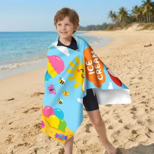Kind in einem Mikrofaser-Strandtuch mit Eiscreme-Motiv an einem sonnigen Strand
