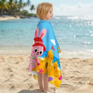 Kind am Strand eingehüllt in ein Mikrofaser-Strandtuch mit süßem Kaninchen-Design.