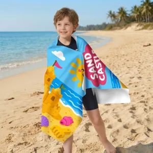 Kind in ein farbenfrohes, schnelltrocknendes Strandtuch mit Sandburg-Print am Strand.