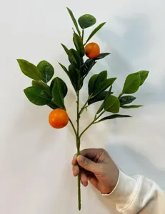 Detail van kunstmatige mandarijnbladeren met twee levendige oranje vruchten