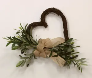 Detailed macro view of a heart-shaped artificial olive wreath with a rustic burlap bow