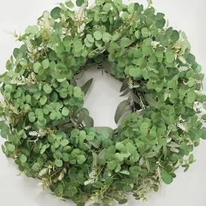 Détail d'une couronne d'eucalyptus artificiel avec des touches florales blanches.