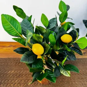 Close-up van een kunstmatige citroenboom met groene bladeren en geel fruit.