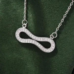 Detailed closeup of a sparkling cubic zirconia infinity pendant necklace on green velvet display.