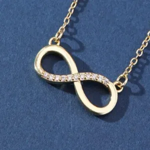 Closeup detail of gold infinity symbol necklace pendant sparkling zirconia crystal refined link.