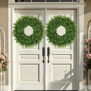 Pair of green artificial boxwood wreaths hanging on a white front door for home decor