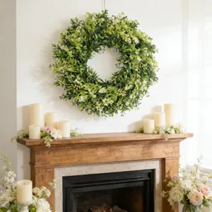 Groene kunstmatige buxuskrans met witte wilde bloemen hangend boven een open haard