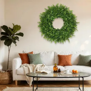 Large green artificial boxwood wreath mounted on a living room wall for home decoration