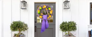 Spring artificial lavender wreath with lemons and purple bow on a white front door