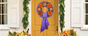 Detail showing a purple and orange floral wreath hanging on a bright yellow front door
