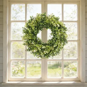 Kunstmatige buxus wildbloemenkrans hangend aan een wit houten kozijn