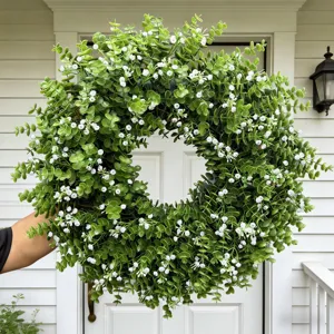 Detailansicht eines künstlichen Eukalyptuskranzes mit weißen Blumen für die Haustür