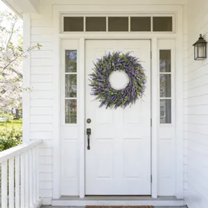 Artificial lavender wreath hanging on a white front door as outdoor home decoration