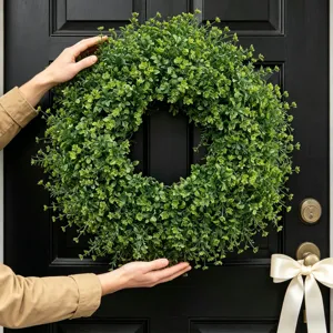 Realistic artificial green boxwood wreath being held for front door home decor