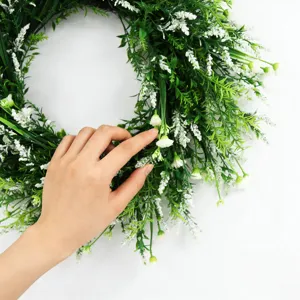 Close-up detail of artificial green wreath with small white flowers for home decor