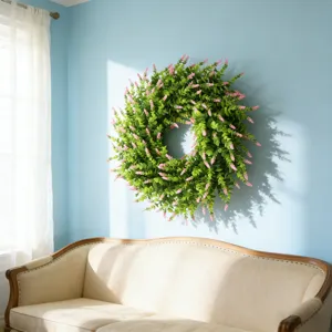 Artificial lavender boxwood wreath hanging on a light blue wall above a cozy sofa