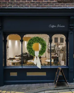 Kunstmatige eucalyptuskrans met witte strik versierd op een raam van een café