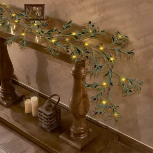 Detailed view of warm LED olive vine garland draped on a wooden console table