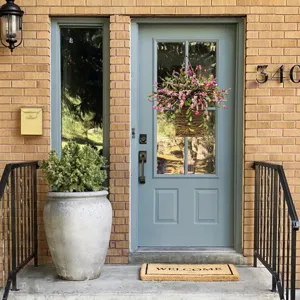 Détail décoratif d'un panier suspendu avec baies roses et fleurs sur une porte bleue