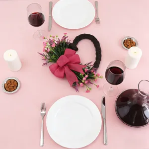 Centrotavola romantico con ghirlanda di fiori a cuore e un grande fiocco rosa.