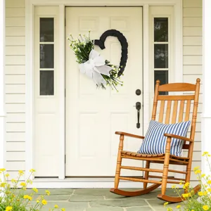 Ghirlanda nera a forma di cuore con fiocco bianco e fiori su una porta d'ingresso