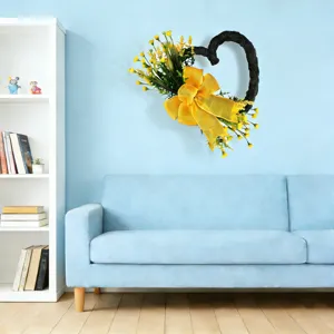 Ghirlanda a forma di cuore con fiori gialli e grande fiocco giallo appesa a una parete blu di casa