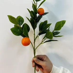 Kunstmatige oranje tak met realistische groene bladeren voor tafeldecoratie in huis