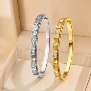 Bracciale rigido vintage texturizzato con strass baguette, elegante gioiello in metallo.