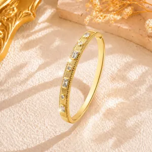Primo piano di un elegante bracciale rigido dorato vintage testurizzato con pietre brillanti.