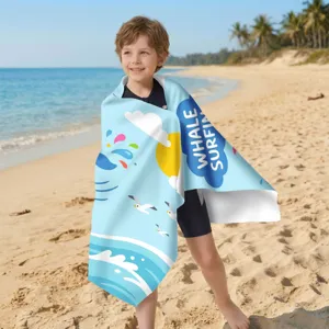 Detailansicht eines Kindes am Strand mit einem Mikrofaser-Handtuch mit Wal-Surf-Motiv.